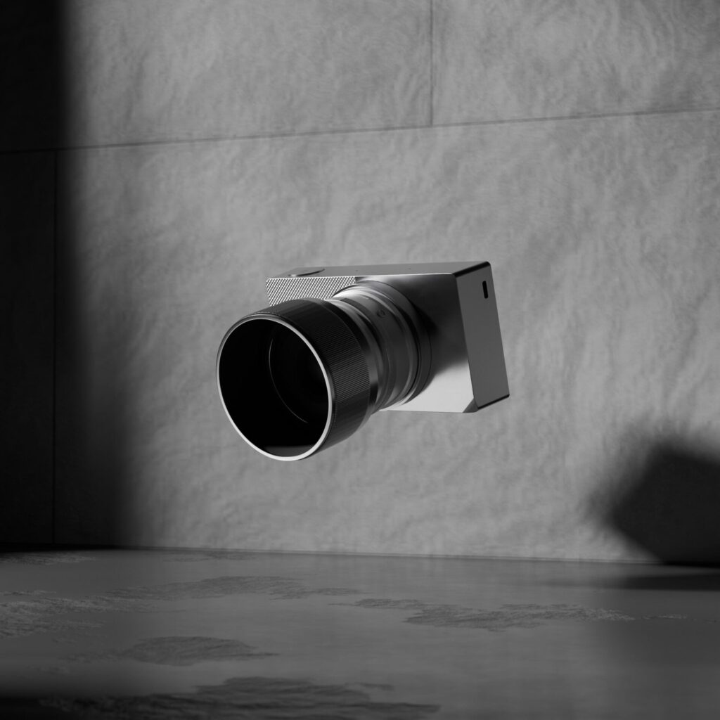 3D-renderöity minimalistinen kamera valaistuna harmaata kiviseinää vasten.